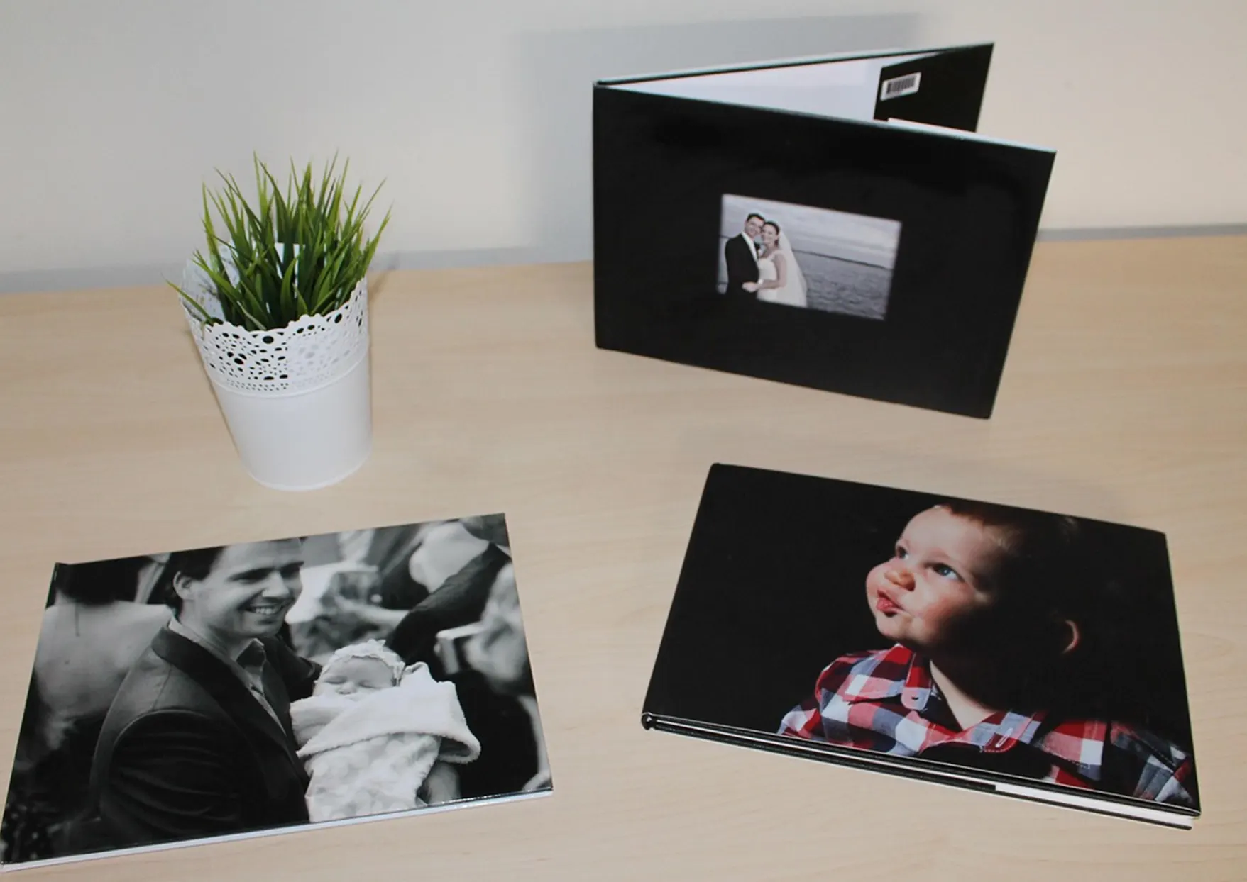 Sur une table sont présentés 3 albums photos personnalisés avec des photos imprimées en couverture.