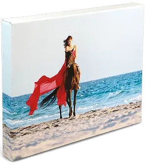 Impression sur toile sur une plage une femme avec un voile rouge fait du cheval